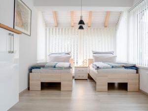 two beds in a bedroom with white walls and windows at Ferienwohnung LenneTraum in Saalhausen