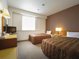 a hotel room with two beds and a television at Bell's Inn Maebashi in Maebashi