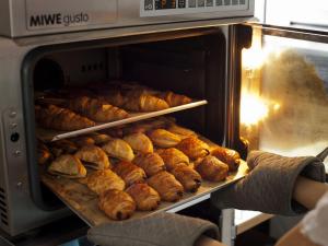a person holding a tray of bread in an oven at Bell's Inn Maebashi in Maebashi