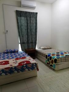 a bedroom with two beds and a window at Homestay An-nur in Alor Setar