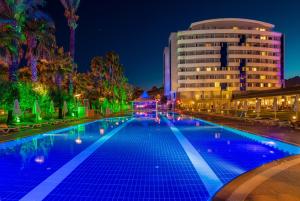 a swimming pool in front of a building at night at Porto Bello Hotel Resort & Spa in Antalya