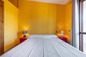 1 dormitorio con paredes amarillas y 1 cama con 2 lámparas en Casa Parigi, en Villasimius