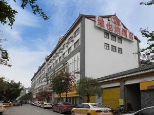 ein großes weißes Gebäude in einer Stadtstraße mit Autos in der Unterkunft Vienna Hotel (Tianyang Old City High Speed Railway Station) in Baise