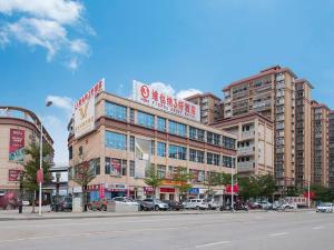 un gran edificio con coches estacionados en un estacionamiento en Vienna 3 Best Hotel (Guangxi Pubei automobile station store), en Pubei