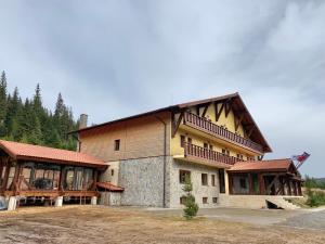 un gran edificio de madera con un gran balcón en Pensiunea Colț din Rai, en Tău Bistra