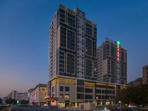 a tall building with a green sign on top of it at Vienna Hotel (Qingyuan Century Bar Shop in Guangdong Province) in Qingyuan