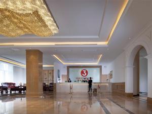 a person standing in a lobby with a sign on the wall at Vienna 3 Best Hotel (Haikou Chengmai Old Town Store) in Chengmai