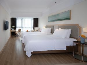 um quarto de hotel com duas grandes camas brancas em Vienna 3 Best Hotel (Haikou Chengmai Old Town Store) em Chengmai