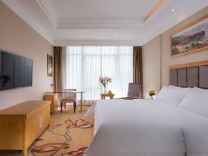 a hotel room with a large bed and a table at Vienna Hotel (Shajinbei Road Fuquan Guizhou) in Fuquan