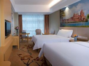 a hotel room with two beds and a flat screen tv at Vienna Hotel(HaiKou High Speed Railway East Station) in Haikou