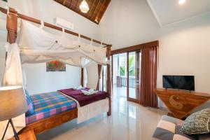 a bedroom with a canopy bed and a tv at Liam Private Villa in Ubud