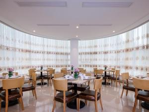杭州的住宿－维也纳国际酒店 (杭州西湖凤山路店)，用餐室配有桌椅和窗帘