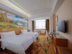 Habitación de hotel con 2 camas y TV de pantalla plana. en Vienna Hotel Huiyang Sanhe Square, en Huizhou