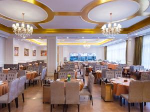 Vienna Hotel conghua jiangpu street branch في هوادو: غرفة طعام بها طاولات وكراسي وثريات