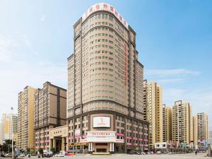 un edificio alto con un reloj en la parte delantera en Vienna International Hotel (Fangchenggang Administration Center High-speed Railway Station branch), en Fangchenggang