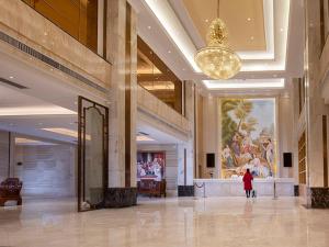 a person walking through a lobby of a building at Vienna Hotel(HaiKou High Speed Railway East Station) in Haikou