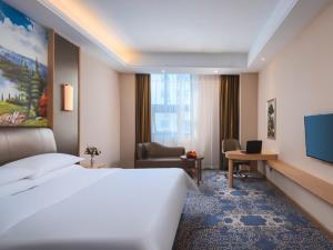 una camera d'albergo con un grande letto e una scrivania di Vienna Hotel (Shanghai jinshanwei Railway Station City Beach Shop) a Jinshan