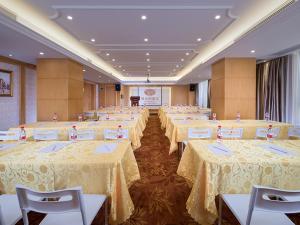 un gran salón de banquetes con mesas y sillas blancas en Vienna Hotel(mei zhou wu hua), en Daba