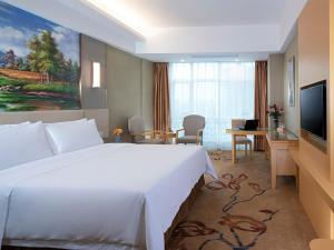 a hotel room with a large white bed and a desk at Vienna Hotel(HaiKou High Speed Railway East Station) in Haikou