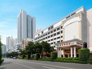 een groot gebouw in een stadsstraat met hoge gebouwen bij Vienna Hotel (Quanzhou Bus Station) in Quanzhou