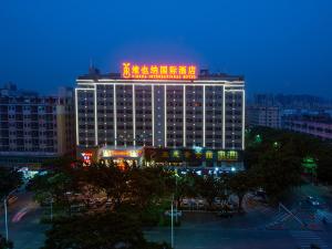 un grand bâtiment avec un panneau en haut dans l'établissement Vienna International Hotel (Shenzhen Fuyong Convention and Exhibition Center), à Fenghuangwei