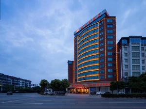 a tall building with a lot of windows in a parking lot at Vienna Hotel(Changshu Sitir Store) in Zhangshu