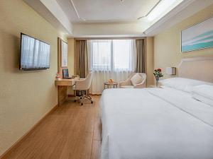 een hotelkamer met een groot bed en een bureau bij Vienna Hotel 3 best Wuwei City south in Wuhu