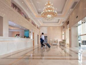 a man walking through a hotel lobby with a suitcase at Vienna Hotel (Jieyang Longwei) in Jieyang
