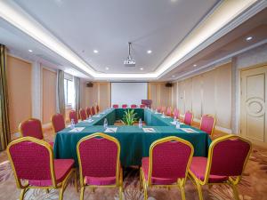 a large conference room with a green table and pink chairs at vienna hotel (HuaZhong Agricultural University in South Lake Store) in Wuhan