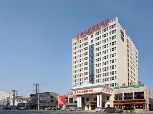 wysoki biały budynek z samochodami zaparkowanymi przed nim w obiekcie Vienna International Hotel (Hunan Changde Taoyuan Longba) w mieście Zhangjiang