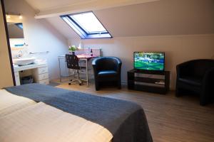 Habitación con cama, TV y mesa. en Gastenverblijf 't Smedenhuys, en Maasbracht
