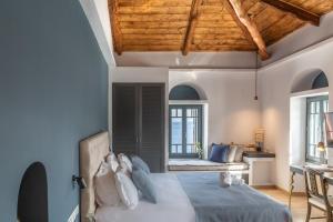 a bedroom with a bed with blue walls and wooden ceilings at CAMARA SUITES in Andros