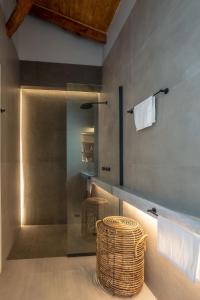 a bathroom with a glass shower with a wicker stool at CAMARA SUITES in Andros