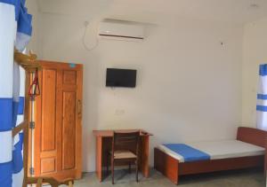 een kamer met een bed, een tafel en een bureau bij D'Villa Garden House in Jaffna