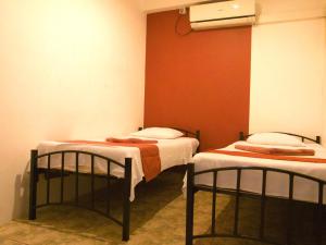 two twin beds in a room with an orange wall at Backpack Lanka in Colombo