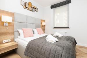 sypialnia z dużym łóżkiem z różowymi poduszkami w obiekcie Apartments Gdańsk Długie Ogrody w Gdańsku