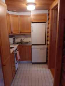 a kitchen with wooden cabinets and a white refrigerator at Pankkotupa 66 "13B" in Savonlinna