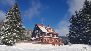 a large red house in the snow with trees at Pension Svoboda in Pec pod Sněžkou