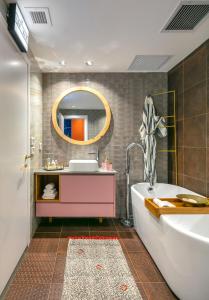 La salle de bains est pourvue d'une baignoire, d'un lavabo et d'un miroir. dans l'établissement Boutique & Comfort in David's Village by FeelHome, à Jérusalem