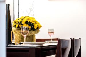a table with two glasses and a vase with yellow flowers at Sea View Apartments 10meters from the beach in Agia Pelagia