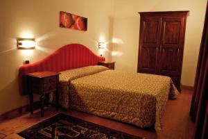 um quarto com uma cama com uma cabeceira vermelha e uma mesa em Hotel Al Barco em Santo Stino di Livenza