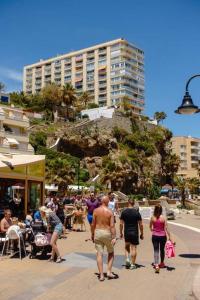 grupa ludzi chodzących po chodniku w pobliżu budynku w obiekcie SUNSET BEACH Charming apartment with jacuzzi w mieście Torremolinos