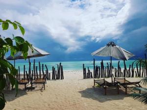 a beach with chairs and umbrellas and the ocean at Meliks in Jambiani