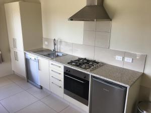 a kitchen with a stove top oven next to a sink at Tuki Vineyard Cottage in Havelock North