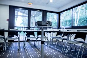 une salle de conférence avec une table et un haut-parleur. dans l'établissement Kyriad Rennes Nord Hotel, à Rennes