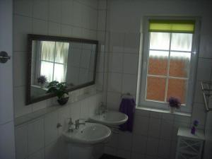 Baño con 2 lavabos, espejo y ventana en Landhaus Kopendorf, en Bojendorf