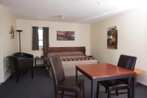 a bedroom with a bed and a table and chairs at Sherborne Motor Lodge in Christchurch
