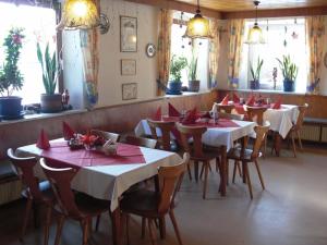 um restaurante com mesas e cadeiras com guardanapos vermelhos em Schwarzer Adler em Schwaighausen