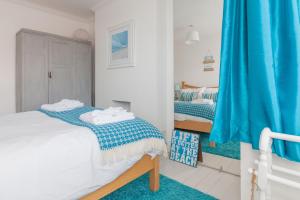 a bedroom with two beds and a blue curtain at Sea Glimpses with garden, beachhut, parking in Broadstairs