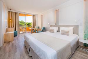a hotel room with a large bed and a table at Marins Beach Club - Adults Only Hotel in Cala Millor